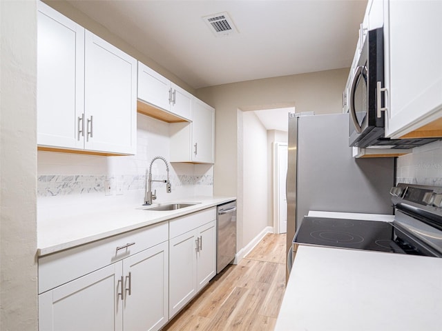 1229 Deneece Ter, Daytona Beach, FL 32117 - kitchen with a sink, appliances with stainless steel finishes, light wood-type flooring, tasteful backsplash, and light countertops