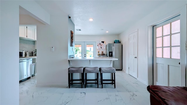 331 Greens End St, Orlando, FL 32810 - kitchen featuring appliances with stainless steel finishes, a kitchen bar, light marble finish floors, white cabinetry, and a peninsula