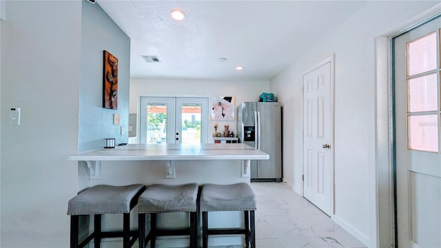 331 Greens End St, Orlando, FL 32810 - kitchen featuring stainless steel fridge with ice dispenser, a kitchen bar, light marble finish flooring, french doors, and a peninsula