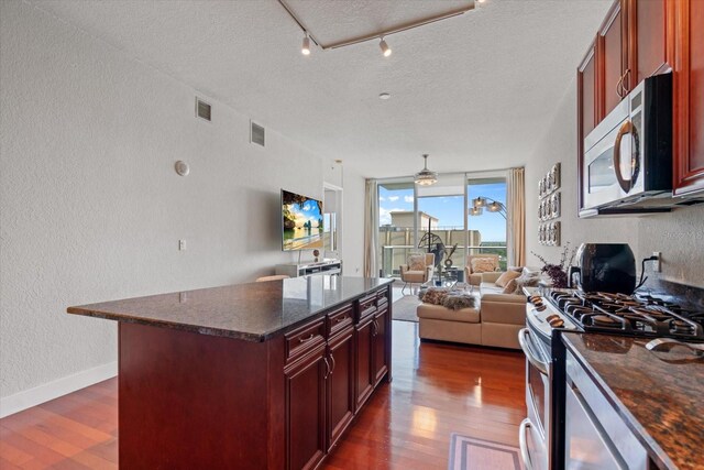 150 E Robinson St Unit 16B-2 # 1605, Orlando, FL 32801 - kitchen featuring appliances with stainless steel finishes, a textured wall, reddish brown cabinets, dark wood-style flooring, and open floor plan