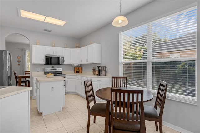 1245 Reagans Reserve Blvd, Apopka, FL 32712 - kitchen with appliances with stainless steel finishes, arched walkways, white cabinetry, a kitchen island, and light tile patterned floors