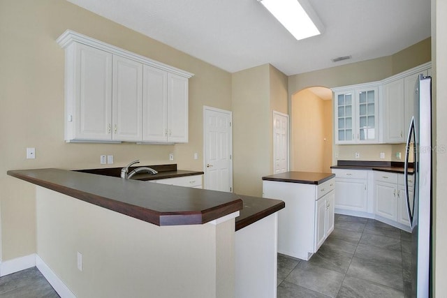 529 Quail Down Dr, Debary, FL 32713 - kitchen with dark countertops, arched walkways, freestanding refrigerator, and a peninsula