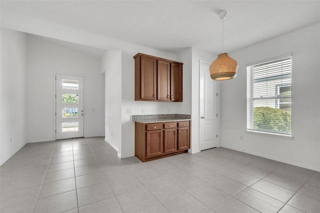 8518 Nemours Pkwy, Orlando, FL 32827 - kitchen featuring light tile patterned floors, brown cabinets, decorative light fixtures, and baseboards
