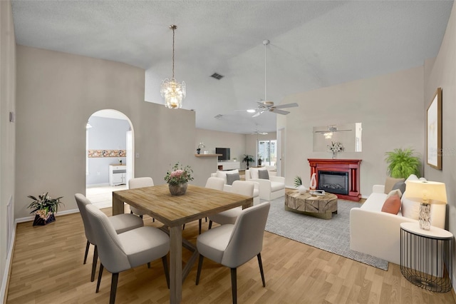 1181 Welch Hill Cir, Apopka, FL 32712 - dining room with arched walkways, a ceiling fan, light wood-style flooring, a fireplace, and high vaulted ceiling