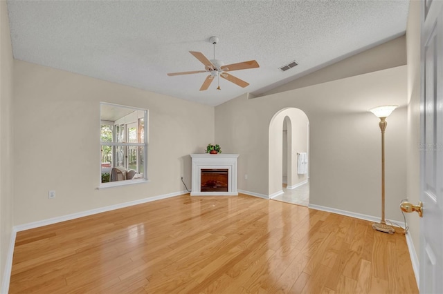 1181 Welch Hill Cir, Apopka, FL 32712 - unfurnished living room with lofted ceiling, a textured ceiling, arched walkways, a ceiling fan, and light wood finished floors
