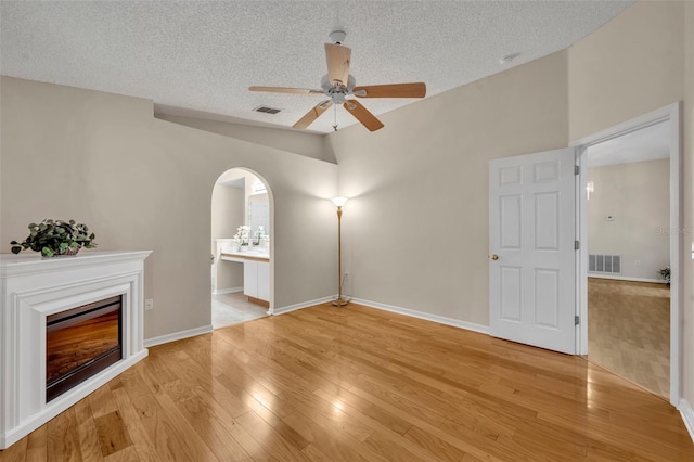 1181 Welch Hill Cir, Apopka, FL 32712 - unfurnished living room featuring lofted ceiling, a textured ceiling, ceiling fan, light wood-style floors, and a glass covered fireplace