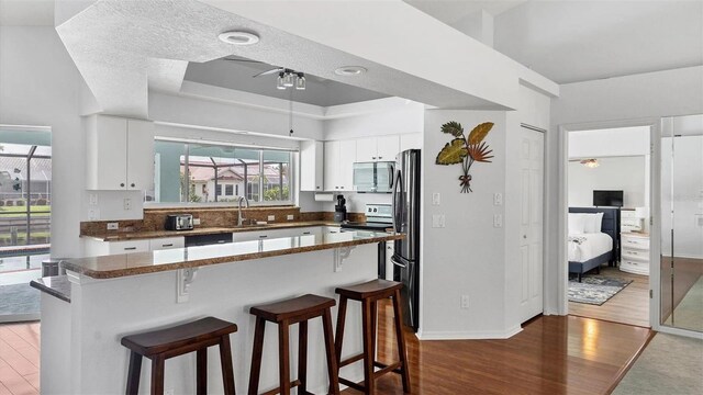 260 Coronado Dr, Punta Gorda, FL 33950 - kitchen featuring stainless steel appliances, dark wood-type flooring, a sink, a ceiling fan, and a breakfast bar
