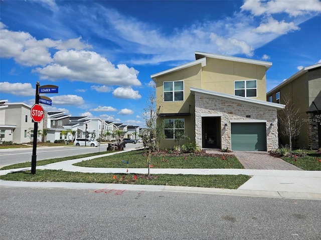 949 Leader St, Davenport, FL 33896 - contemporary home featuring stone siding, decorative driveway, a residential view, stucco siding, and an attached garage