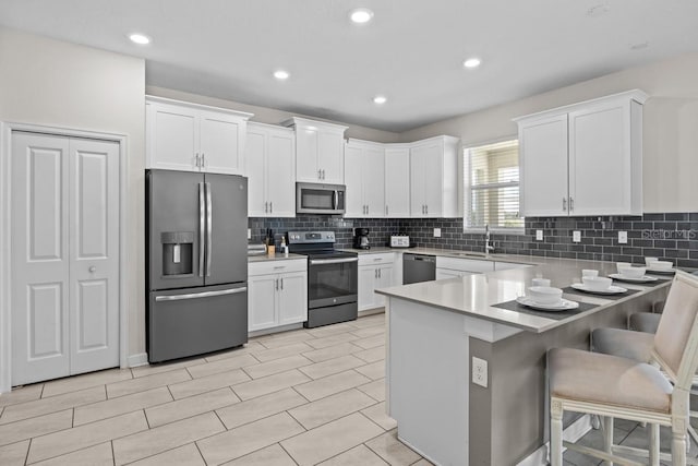 8822 Interlocking Ct, Davenport, FL 33896 - kitchen with appliances with stainless steel finishes, white cabinetry, a kitchen breakfast bar, tasteful backsplash, and recessed lighting
