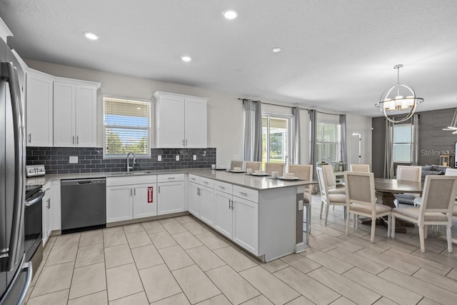 8822 Interlocking Ct, Davenport, FL 33896 - kitchen with appliances with stainless steel finishes, a sink, a chandelier, a peninsula, and tasteful backsplash