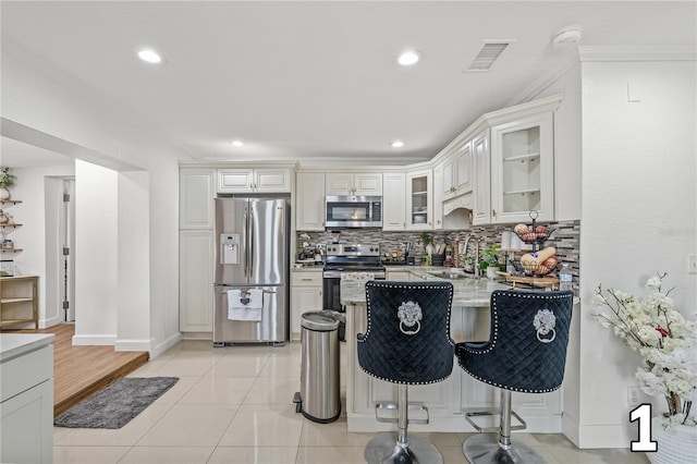 10227 Parsons St, Tampa, FL 33615 - kitchen with appliances with stainless steel finishes, a sink, tasteful backsplash, glass insert cabinets, and a kitchen bar