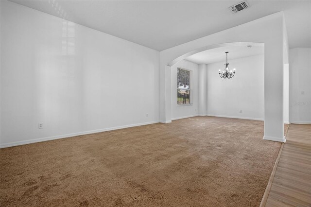 12824 Cloverdale Ln, Clermont, FL 34711 - carpeted spare room featuring arched walkways, a chandelier, and wood finished floors