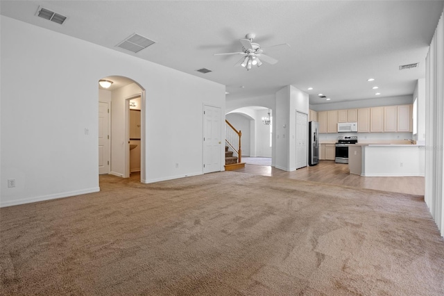 12824 Cloverdale Ln, Clermont, FL 34711 - unfurnished living room with arched walkways, light carpet, a ceiling fan, stairs, and recessed lighting