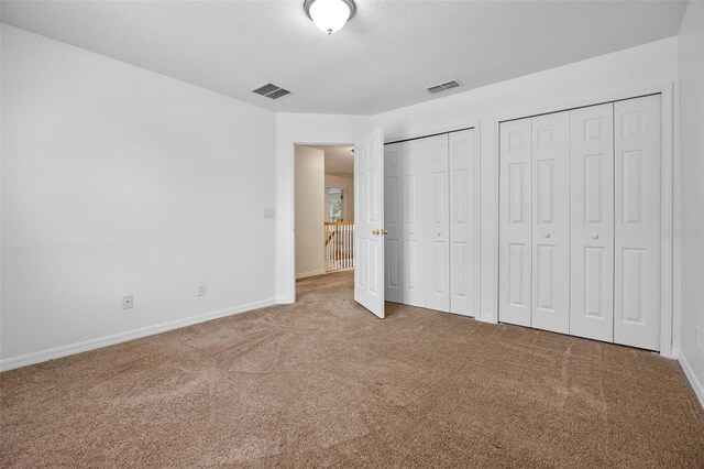 12824 Cloverdale Ln, Clermont, FL 34711 - unfurnished bedroom with two closets, carpet floors, and a textured ceiling
