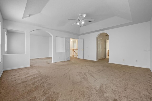 12824 Cloverdale Ln, Clermont, FL 34711 - empty room featuring a raised ceiling, arched walkways, a ceiling fan, and carpet