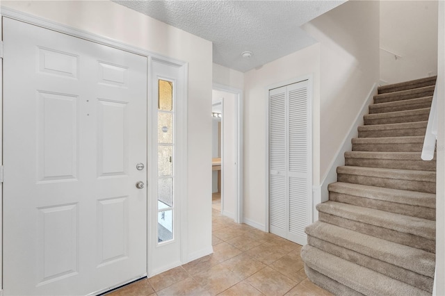 9145 Fort Jefferson Blvd, Orlando, FL 32822 - foyer featuring stairway, a textured ceiling, light tile patterned flooring, and baseboards
