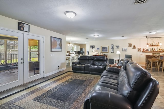 704 Tangerine Ct, Winter Garden, FL 34787 - living area featuring a chandelier, french doors, bar, a textured ceiling, and baseboards