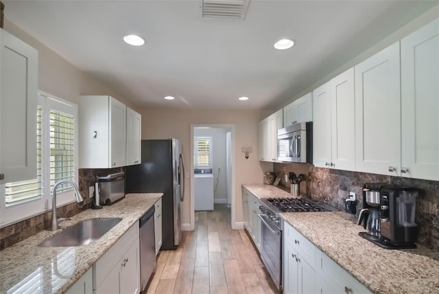 704 Tangerine Ct, Winter Garden, FL 34787 - kitchen with appliances with stainless steel finishes, washer / clothes dryer, a sink, decorative backsplash, and recessed lighting