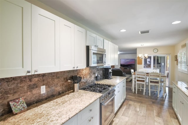 704 Tangerine Ct, Winter Garden, FL 34787 - kitchen featuring stainless steel appliances, a chandelier, backsplash, light wood finished floors, and light stone countertops
