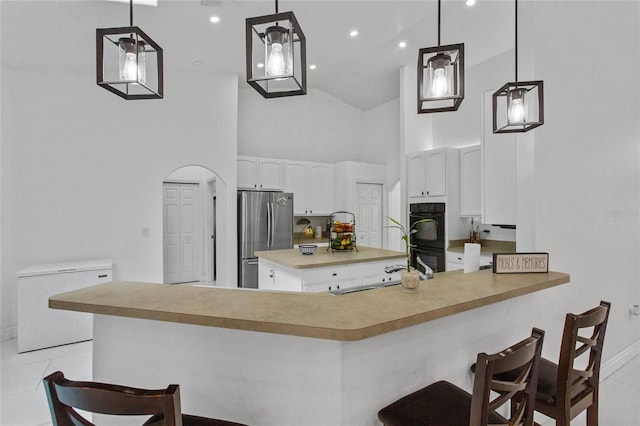 4905 Emilee Grace Ln, Saint Cloud, FL 34771 - kitchen featuring freestanding refrigerator, a sink, high vaulted ceiling, white cabinetry, and a breakfast bar area