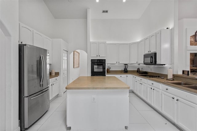4905 Emilee Grace Ln, Saint Cloud, FL 34771 - kitchen with black appliances, light tile patterned floors, white cabinets, and a high ceiling