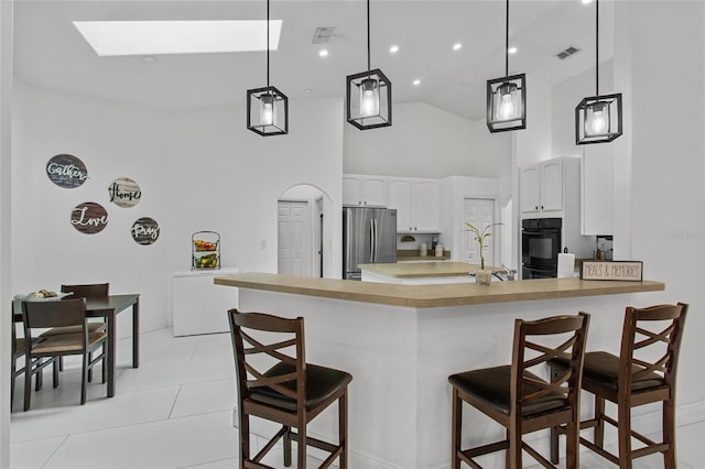 4905 Emilee Grace Ln, Saint Cloud, FL 34771 - kitchen featuring freestanding refrigerator, high vaulted ceiling, a skylight, white cabinetry, and light countertops