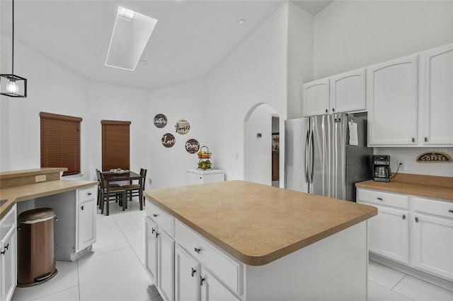 4905 Emilee Grace Ln, Saint Cloud, FL 34771 - kitchen with freestanding refrigerator, light tile patterned flooring, arched walkways, white cabinets, and a skylight