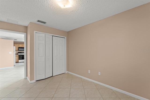 476 Basking Ridge Ct, Ocoee, FL 34761 - unfurnished bedroom featuring a textured ceiling, light tile patterned floors, a closet, baseboards, and freestanding refrigerator