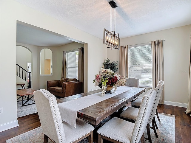 18109 Kara Ct, Tampa, FL 33647 - dining room featuring dark wood finished floors, baseboards, stairway, a textured ceiling, and arched walkways