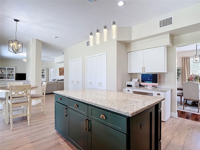 18109 Kara Ct, Tampa, FL 33647 - kitchen featuring light wood-style floors, white cabinets, a textured ceiling, a chandelier, and pendant lighting