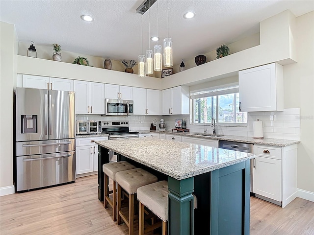 18109 Kara Ct, Tampa, FL 33647 - kitchen with appliances with stainless steel finishes, a sink, light wood finished floors, a center island, and white cabinetry