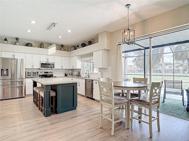 18109 Kara Ct, Tampa, FL 33647 - kitchen featuring stainless steel appliances, light wood finished floors, white cabinets, a chandelier, and a center island