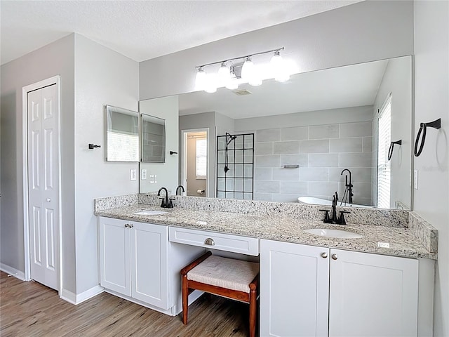 18109 Kara Ct, Tampa, FL 33647 - full bath featuring wood finished floors, double vanity, tiled shower, baseboards, and a closet