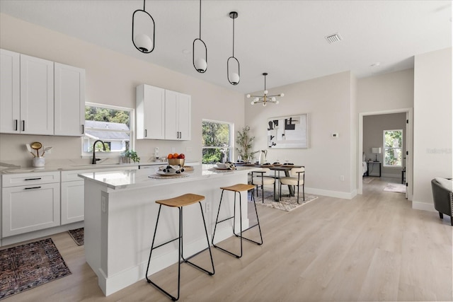 811 E Mcdonald Ave, Eustis, FL 32726 - kitchen with light wood-type flooring, a breakfast bar, white cabinets, and a sink
