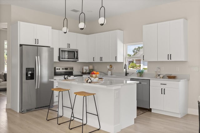811 E Mcdonald Ave, Eustis, FL 32726 - kitchen with stainless steel appliances, light wood-style flooring, a center island, and white cabinets