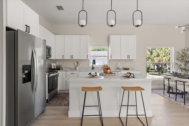 811 E Mcdonald Ave, Eustis, FL 32726 - kitchen featuring appliances with stainless steel finishes, a sink, a kitchen bar, a center island, and light wood-style floors