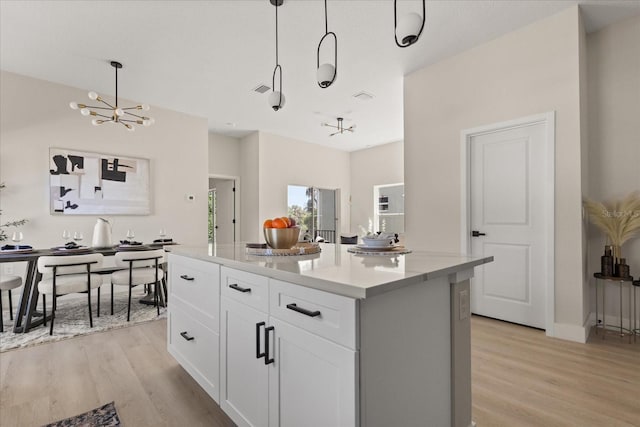 811 E Mcdonald Ave, Eustis, FL 32726 - kitchen featuring a chandelier, light wood finished floors, white cabinets, and a center island