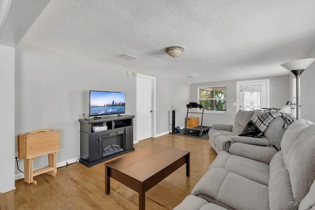 232 E Grant St, Orlando, FL 32806 - living area with light wood finished floors, a textured ceiling, and baseboards