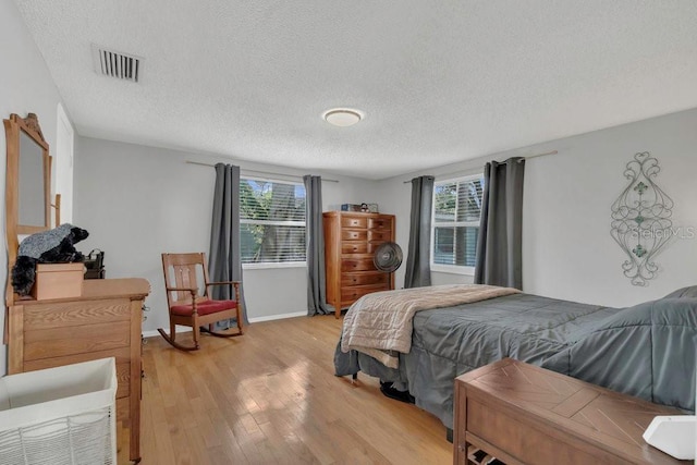 232 E Grant St, Orlando, FL 32806 - bedroom with light wood-style floors, multiple windows, a textured ceiling, and baseboards