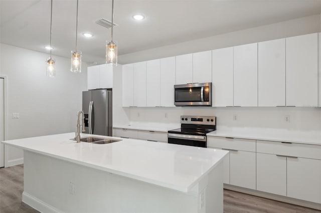 10218 N Langdon Rd, Citrus Springs, FL 34434 - kitchen featuring appliances with stainless steel finishes, light wood-style flooring, a sink, an island with sink, and white cabinetry
