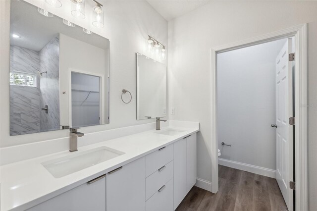 2565 W Laredo Dr, Citrus Springs, FL 34433 - bathroom with double vanity, wood finished floors, a tile shower, toilet, and baseboards