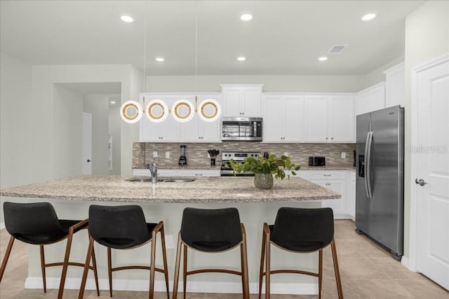 4310 Lana Ave, Davenport, FL 33897 - kitchen with appliances with stainless steel finishes, a sink, decorative backsplash, white cabinetry, and a kitchen breakfast bar