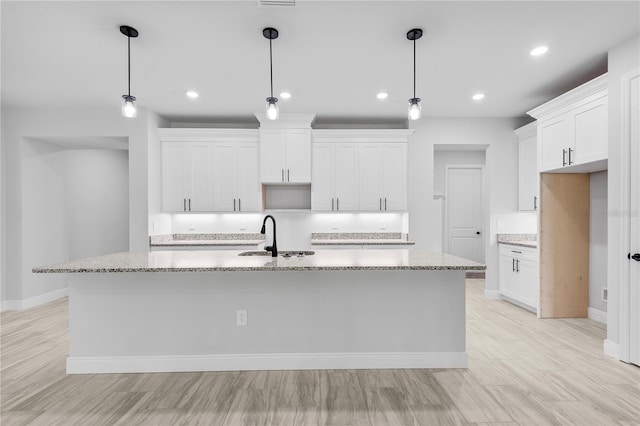 30369 Apricot Ave, Eustis, FL 32736 - kitchen featuring white cabinets, a kitchen island with sink, light stone countertops, recessed lighting, and decorative light fixtures