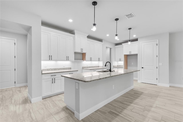 30369 Apricot Ave, Eustis, FL 32736 - kitchen with an island with sink, white cabinetry, light stone countertops, recessed lighting, and hanging light fixtures
