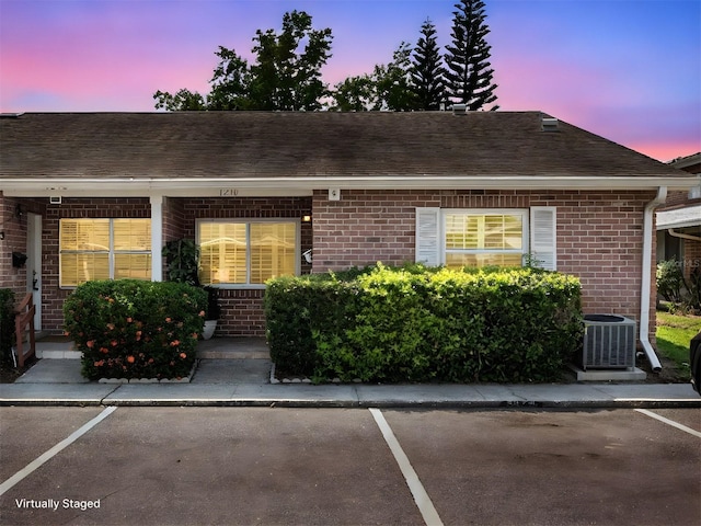 1230 Americana Pl, Orlando, FL 32807 - view of front of property featuring central AC, brick siding, uncovered parking, and roof with shingles