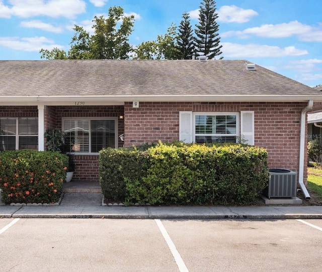 1230 Americana Pl, Orlando, FL 32807 - view of front of home with central AC, brick siding, uncovered parking, and roof with shingles