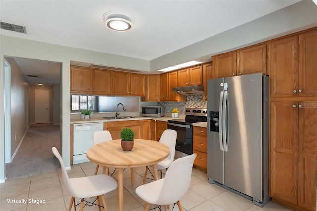 1230 Americana Pl, Orlando, FL 32807 - kitchen featuring appliances with stainless steel finishes, under cabinet range hood, light countertops, brown cabinets, and light tile patterned flooring
