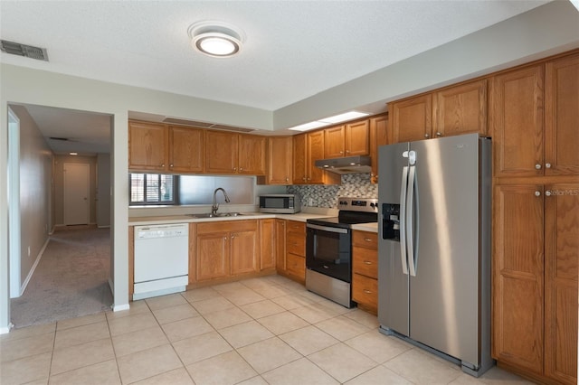 1230 Americana Pl, Orlando, FL 32807 - kitchen featuring stainless steel appliances, under cabinet range hood, light countertops, a sink, and brown cabinets