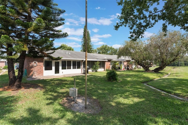 1230 Americana Pl, Orlando, FL 32807 - rear view of house featuring a lawn, brick siding, and a sunroom