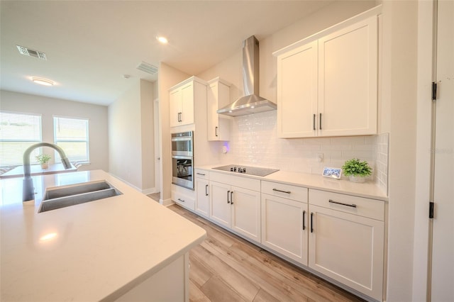 16055 Silver Brook Way, Winter Garden, FL 34787 - kitchen with wall chimney exhaust hood, black electric stovetop, a sink, light wood-style flooring, and decorative backsplash